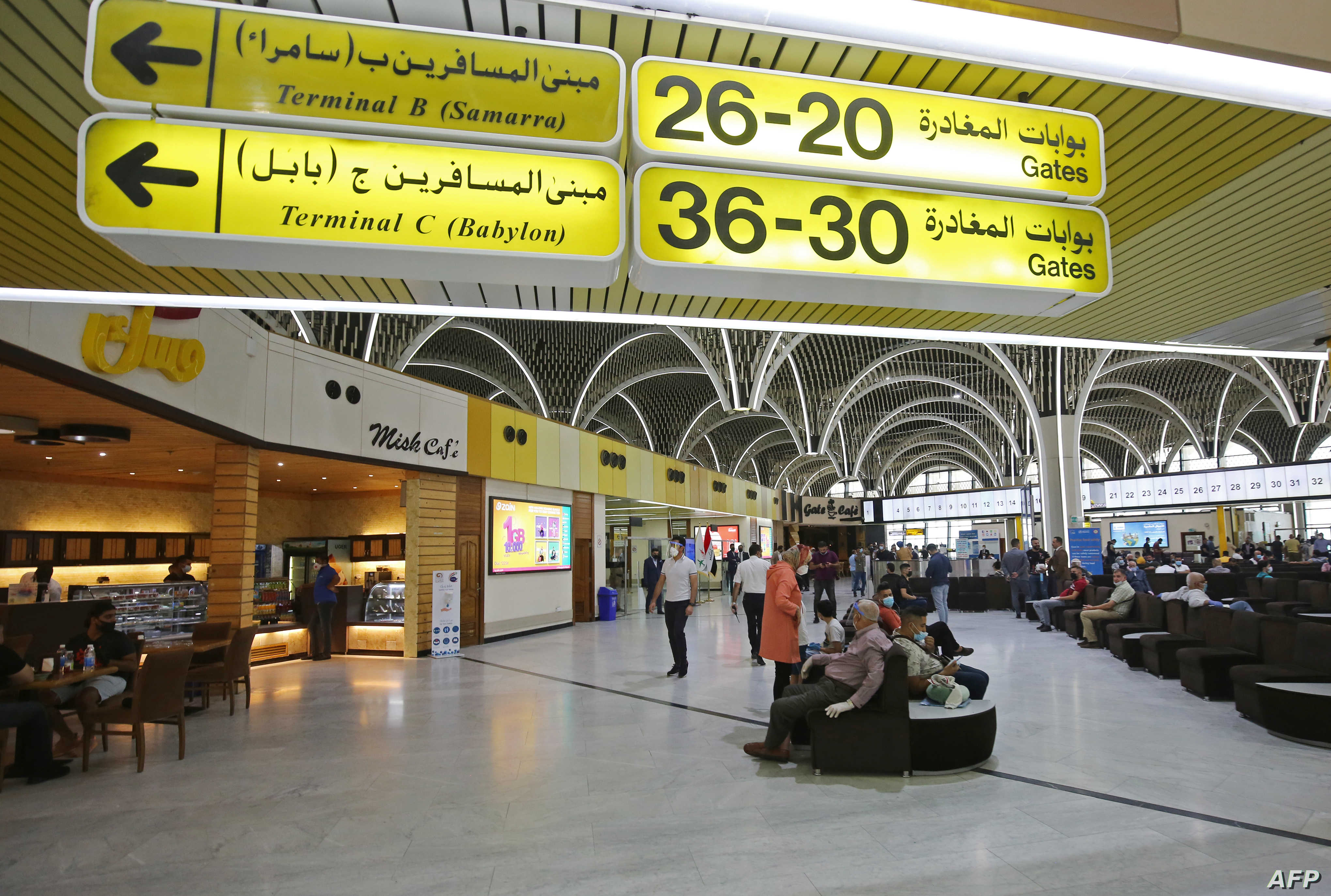 Passengers wearing protective masks wait for flights at the departure hall of Baghdad international airport following its reopening on July 23, 2020, after a closure forced by the coronavirus pandemic restrictions aimed at preventing the spread of the deadly COVID-19 illness in Iraq. (Photo by AHMAD AL-RUBAYE / AFP)